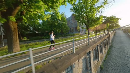 Caucasian Woman Runs Along the Embankment