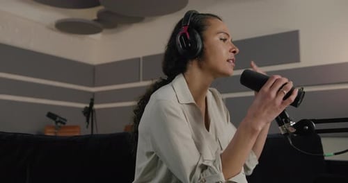 Young Adult Female Podcaster in Studio Recording Podcast on Sofa