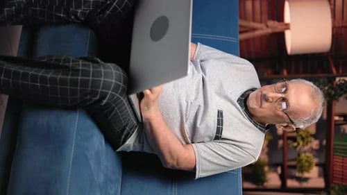 Senior Man Relaxing on Couch with Laptop