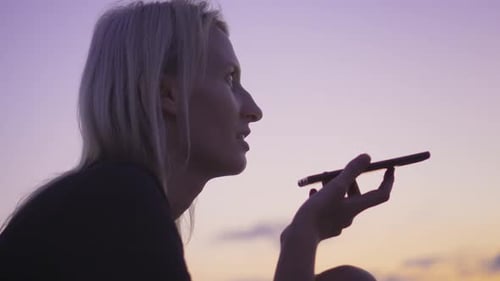 Woman dictates message using voice recognition on street on smartphone.