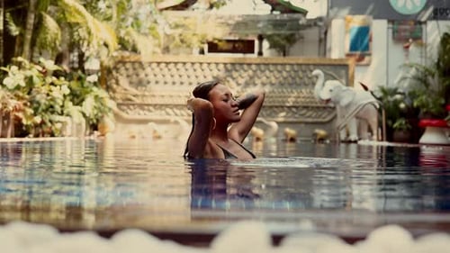 Woman Relaxing in Tropical Swimming Pool in Resort