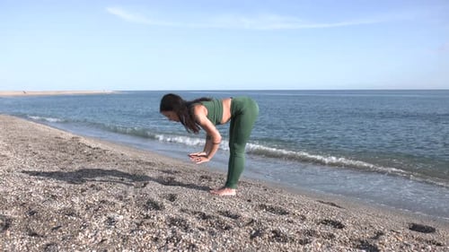 Young Woman Performing Uttanasana Pose on the Beach