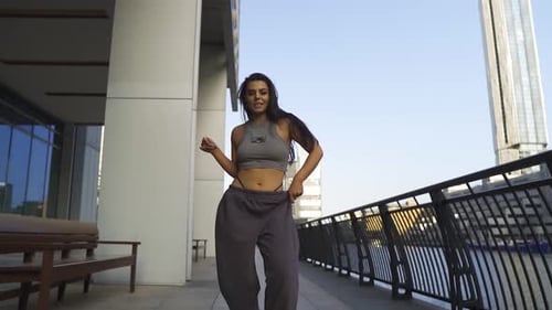 Street dancer female maintain dancing while walking towards the camera with confidence smiling frees
