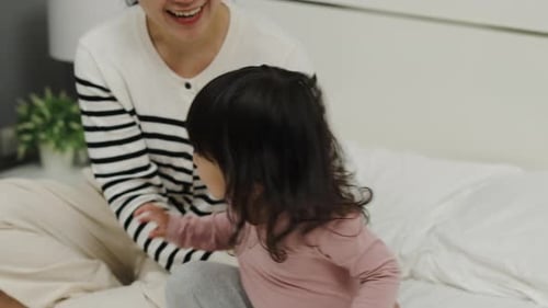 Cheerful Mother and Child Playing on Bed