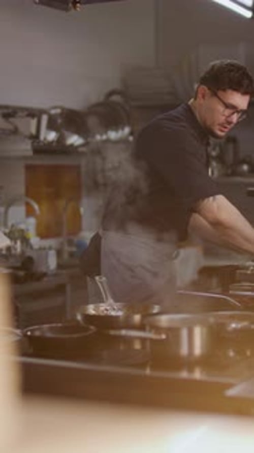 Chef Preparing Dish and Coordinating Colleague in Restaurant Kitchen