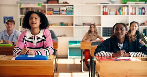 Teenage students raising hands in classroom during lesson