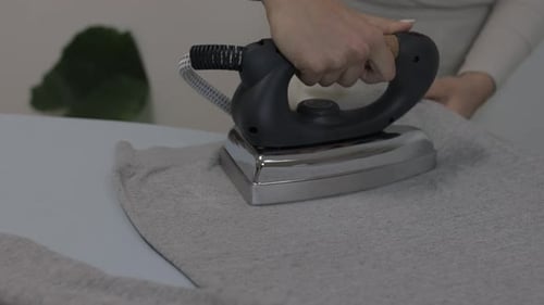 Close up of female hands ironing clothes with iron on an ironing board. slow motion, 4k footage