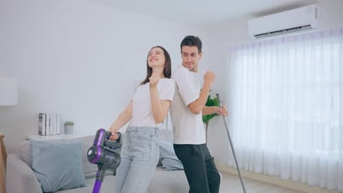 Couple Dancing With Vacuum and Mop at Home