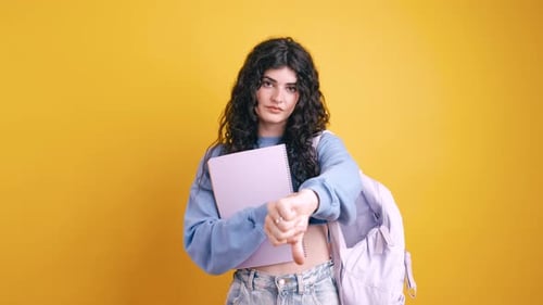 Student Showing Thumbs Down on Yellow Background