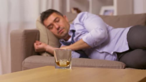 Man Drinks Whiskey While Lying on Couch