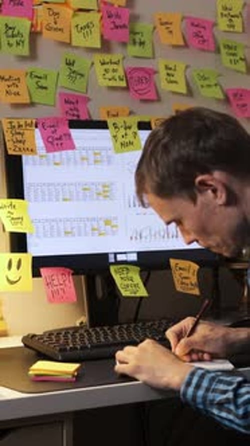 Man Sticks Note to Monitor at His Desk