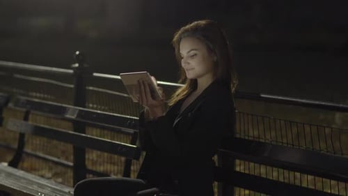 Young Woman Using Tablet Computer In The Park At Night