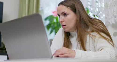 Shocked Woman Reacting to Laptop Screen at Home