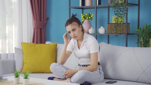Woman Sitting on Sofa Looking Thoughtful
