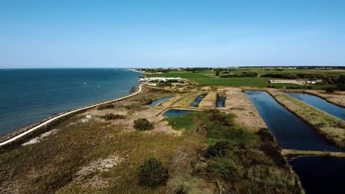 Aerial view from a drone over the sea and salt marshes, with surrounding fields, nature, sunny