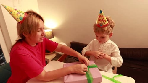 Woman Unties Ribbon on Birthday Gift with Child