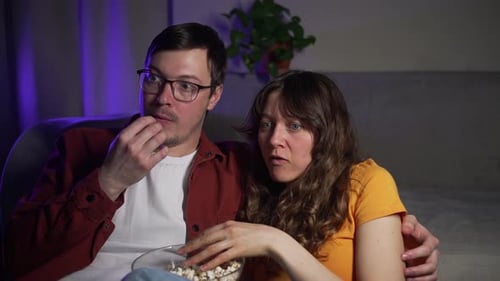 Couple Watching Scary Movie at Home, Eating Popcorn
