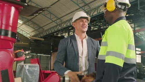 Black engineer handshakes with customer with robotic arm in a smart factory.