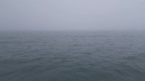 Aerial View of Calm Ocean Waves Disappearing Into Thick Fog