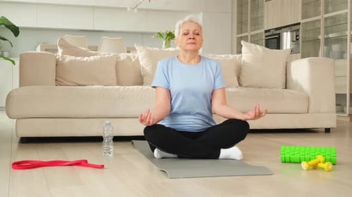 Senior Woman Meditating at Home with Fitness Equipment