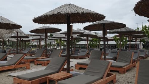 Comfortable Sun Loungers with Umbrellas on Empty Beach in Cloudy Day No People