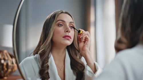 Young Woman Applies Mascara in Mirror, Getting Ready