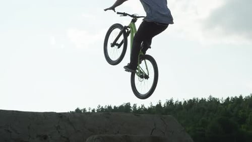 Young Adult Biker Performing Stunt on Dirt Ramp