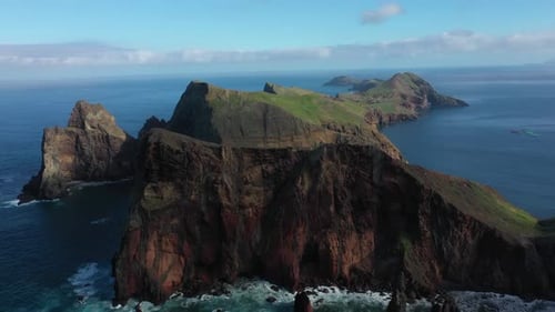 Drone shot of the steep cliff with red stone and big black lines and patterns in Madeira.