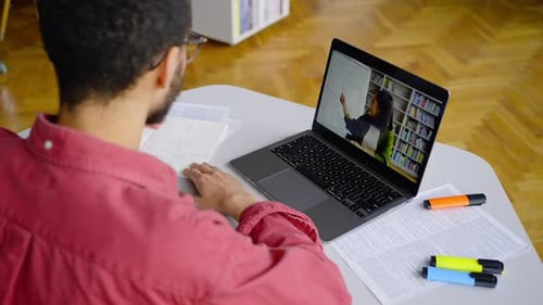 Rear View of a Multiethnic Male Student During an Online Lesson By Video Link