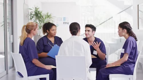 Video of diverse group of male and female doctors sitting in discussion in hospital meeting