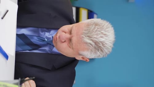 Senior Businessman Struggles to Stay Awake at Desk