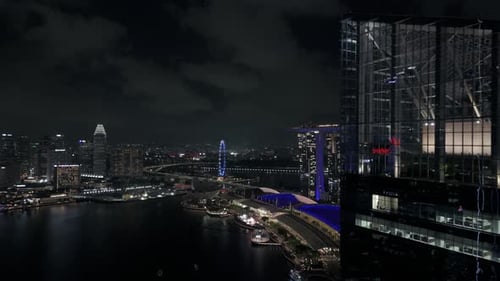 Marina Bay Sands revealed behind tall building, Singapore flyer and more, night drone shot