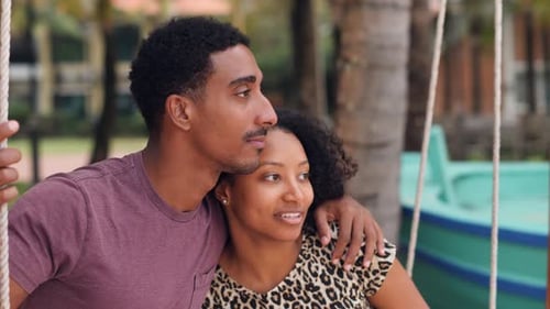 Intimate Young Couple Sitting on a Swing at the Beach Enjoying Talks and Laughs
