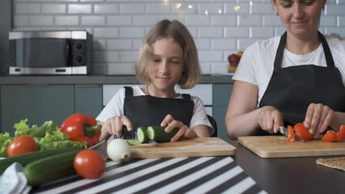 Niña con mamá cortando pepinos y pimientos