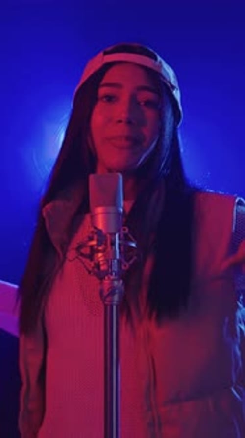 Enthusiastic Young Woman Singing into Microphone with Colorful Lighting