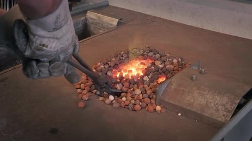 Gloved Hands Adjust Metal in Fiery Blacksmith Forge