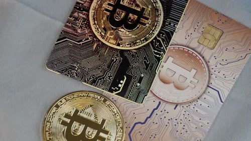 Bitcoin-Kreditkarten und -Münzen drehen sich auf grauer Stoffoberfläche