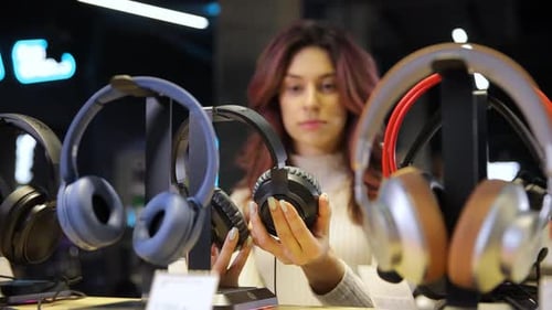 Woman with Curly Hair Choosing Headphones in Speaker System Store