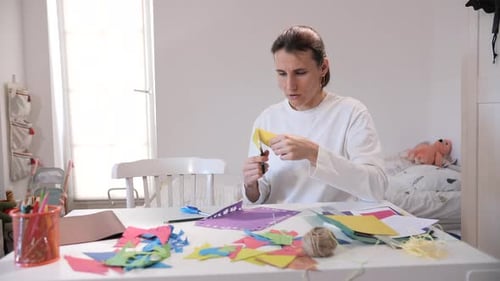 Woman Cuts Paper at Table with Scissors for Craft