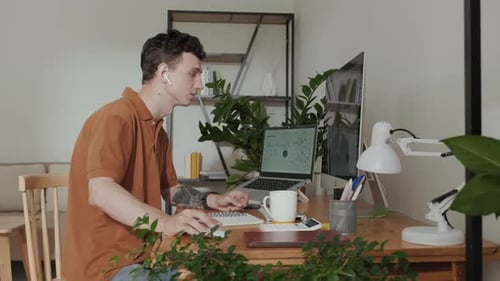 Jeune employé de sexe masculin prenant des notes et communiquant avec un collègue