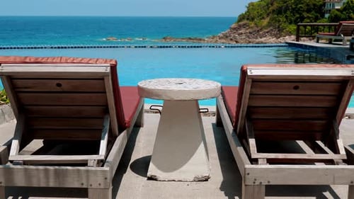 Empty Beach Chairs and a Cocktail Table By the Pool