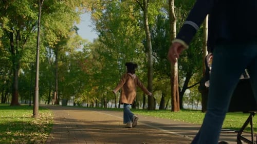 Relaxed Parents Walking Park Pushing Baby Stroller Rear View. Happy Family Day