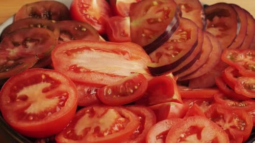 Schneiden Sie bunte Bio-Tomaten auf einem Schreibtisch aus Holz, mischen Sie den Hintergrund aus Tomaten, verschiedene Sorten in Scheiben