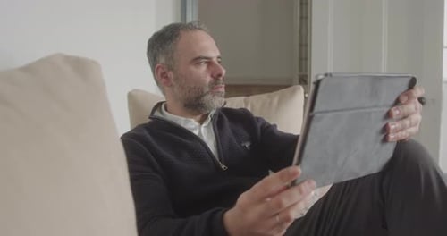 Man Relaxes with Tablet on Couch Indoors