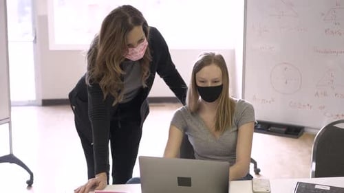 High School Teacher and Student in Face Masks at Laptop in Classroom Adult
