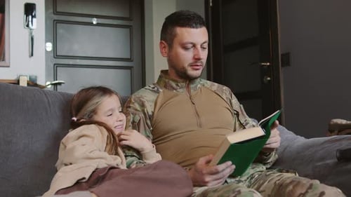 Dad in Military Uniform Reading Book to Daughter