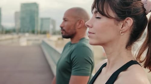 Side view of an active healthy couple does shoulders exercises outdoors before working out