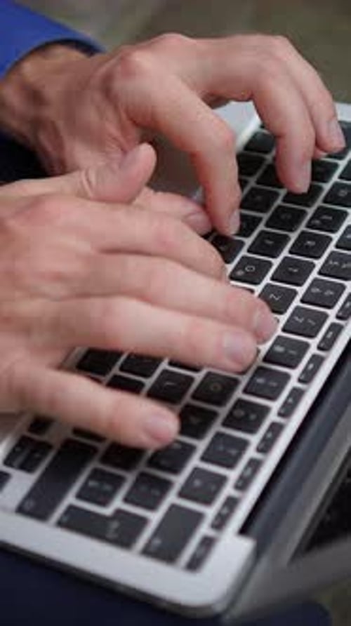 Une vue rapprochée des mains qui tapent activement sur le clavier d'un ordinateur portable pendant qu'elles sont au travail