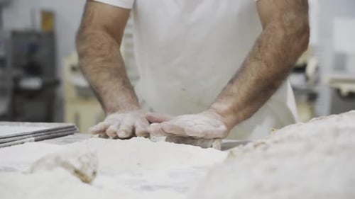Busy bakery chef rolling dough in flour to prepare a tasty and delicious pastry