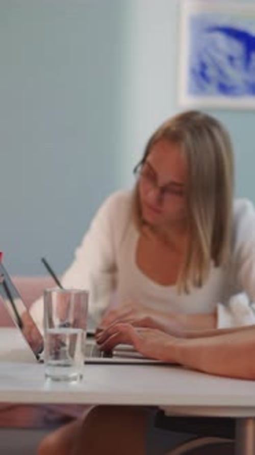 Woman Listens to Music in Headphones While Friend Studying